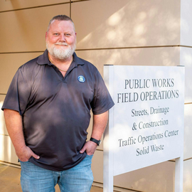 Dale May standing next to Public Works sign in front of building