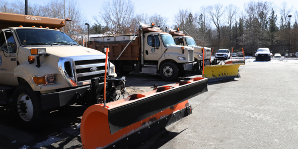 Public Works trucks with plows on the front parked in a parking lot