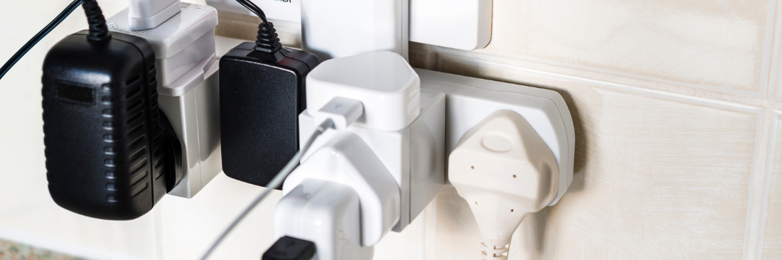 Lots of plugs plugged into a surge protector on a wall