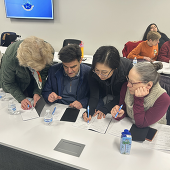People sitting at a table comparing their notes in a notebook