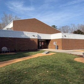 Community Center building facade with bench and cornhole boards in the foreground