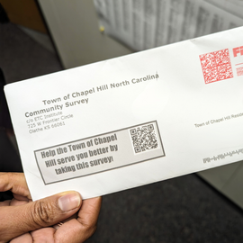 Hand holding a community survey envelope