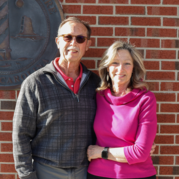 Image of a man and woman, standing in front of a brick wall. 
