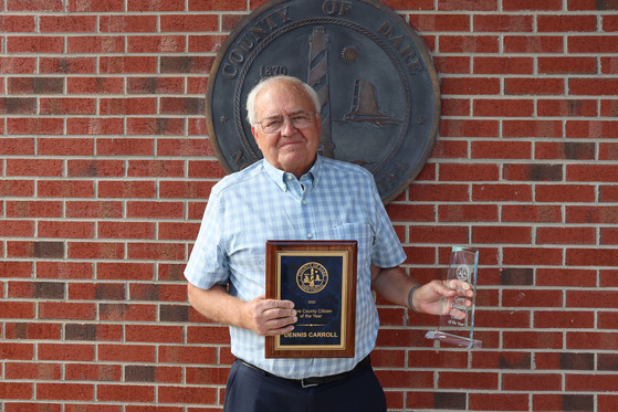 Image of Dennis Carroll holding his Citizen of the Year plaque and trophy.
