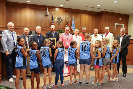 Image of girls 8U team standing with the Dare County Board of Commissioners.