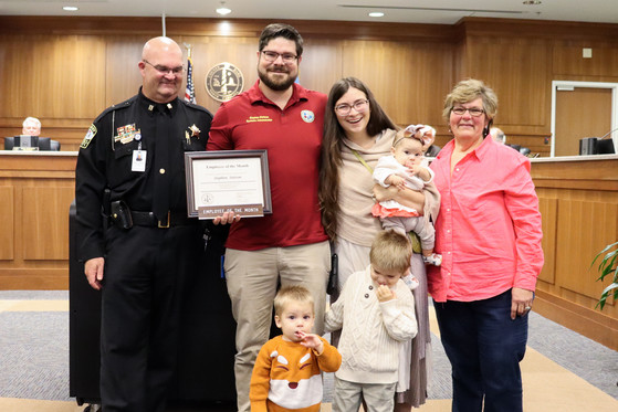 Image of Stephen Stetson and his family standing with Jack Scarborough in front of the Dare County board room.