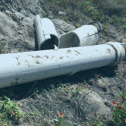 Image of broken PVC pipes laying in the sand.