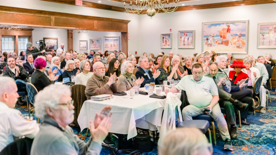 Image of a crowded room of applauding people.