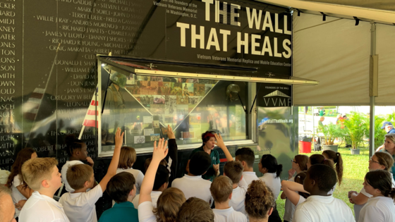 Image of an educator speaking to a group of young boys in front of an exhibit.