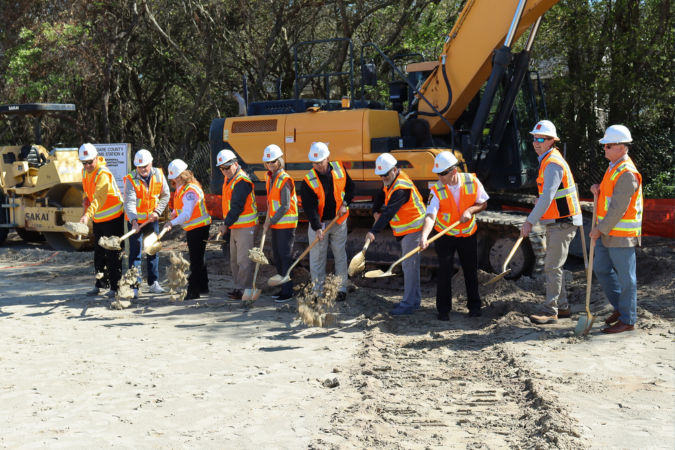Image of a line of people breaking ground ceremoniously with shovels.