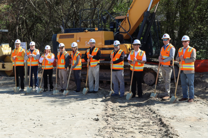 Image of a line of people breaking ground ceremoniously with shovels.