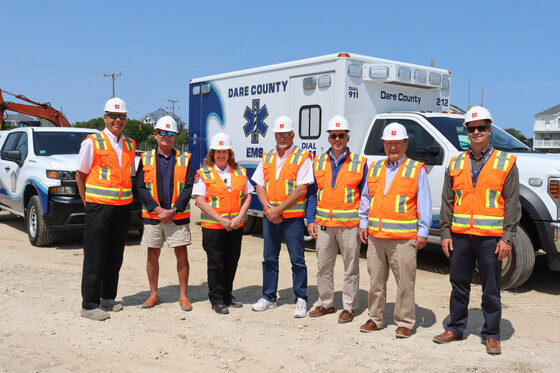 Dare County Commissioners and county officials stand in front of a Dare County ambulance on the site of the new facility.