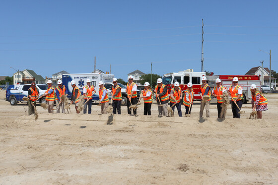 Image of a line of county and town officials holding shovels filled with sand.