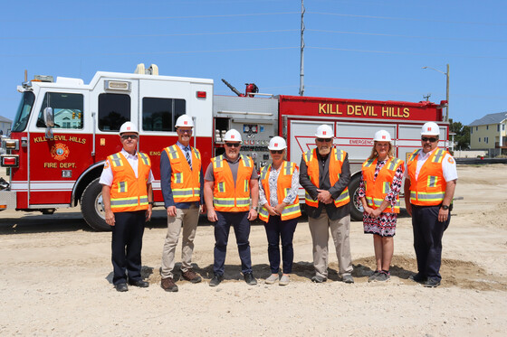 Image of the Kill Devil Hills Commissioners and Fire officials standing in front of a fire truck on the new facility site.