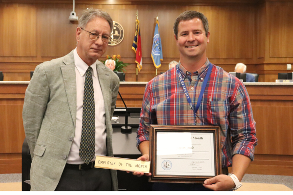 Image of Finance Director and Deputy County Manger David Clawson presents a framed certificate to Dustin Peele.