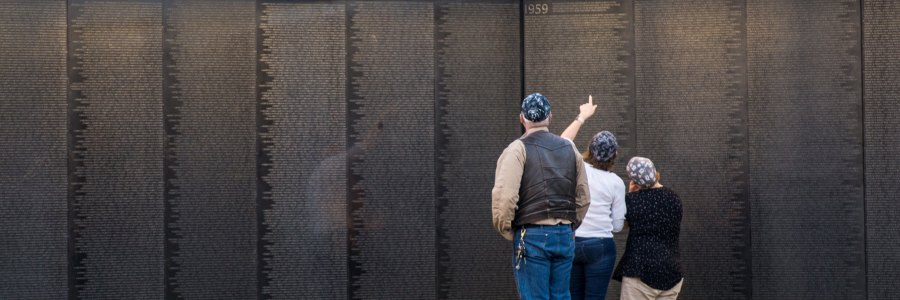 Image of a family visiting The Wall That Heals, looking at the names on the wall.