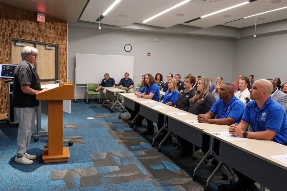 Image of the graduates listening to Robin Harris, COA Dean of Health Sciences and Wellness Programs, speak.