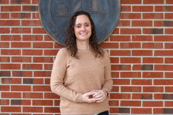 Image of Allison Woodard standing in front of a brick wall.