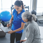 Image of a fitness coordinator performing an assessment of an individual in a gym