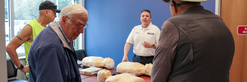 Image of an EMS employee showcasing hands-only CPR procedures for attendees during the open house event.