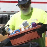 Image of a man with a beard throwing old cans of paint and cleaning chemicals into a garbage can.