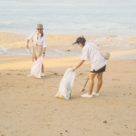 Image of two women picking up trash on the beach.