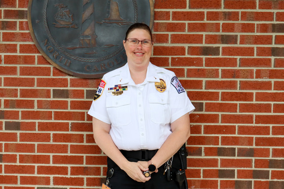 Image of Kimberly dressed in her EMS uniform, holding her service pin.