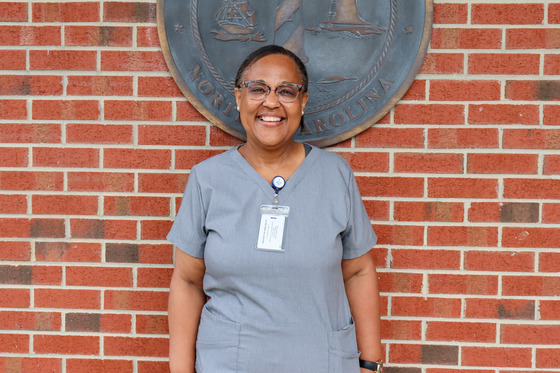 Image of Sectina standing in front of a brick wall in her nurse uniform. 