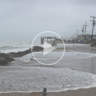 Image of ocean washing over N.C. Hwy. 12. A "play' symbol signifies that clicking this image will play a video.