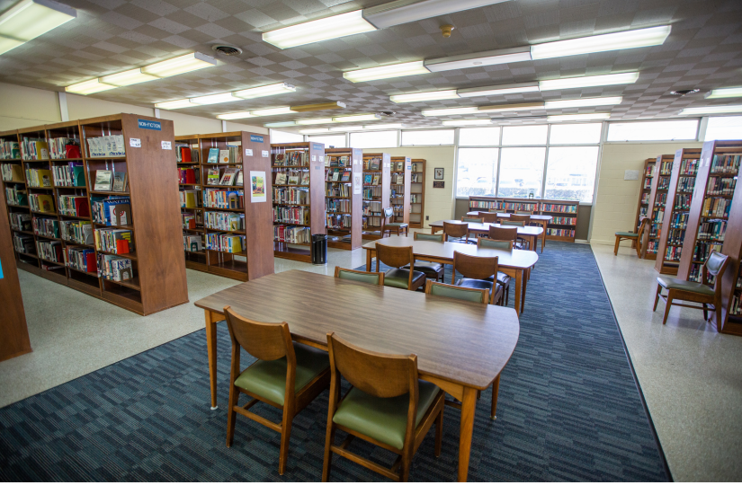 Image of the interior of the Kill Devil Hills Library featuring a seating area and rows of bookshelves.