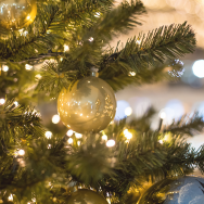 Close up image of gold ornaments and lights on a Christmas tree.