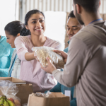 Image of a woman handing a man food at a food pantry.