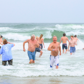 Image of people running in and out of a chilly ocean.
