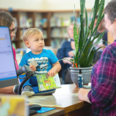 Image of a small child checking out a book at the Manteo library.