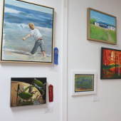 Image of art displayed on a wall with ribbons pinned beside some pieces.