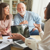 Image of someone helping an elderly couple with their taxes.