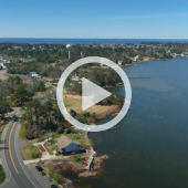 Aerial image of Colington Island. A play button signifies that a video will play when clicked. 