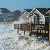 Image of waves crashing into houses along the beach on Hatteras Island during a hurricane.