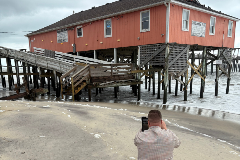 Image of a damage assessor taking photos of a home on the ocean.