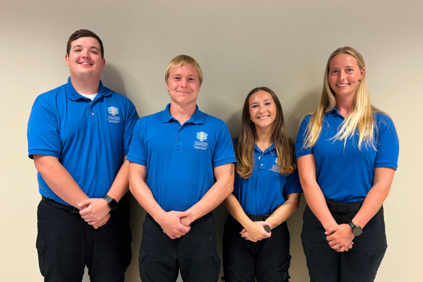 Image of the four graduates in blue shirts