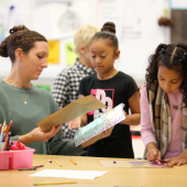 Image of a teacher viewing a young student's drawings