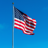 Image of a USA flag flying on a tall flag pole.