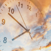 Image of a clock face reflecting the sky.