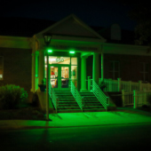 Image of the Virginia S. Tillett Community Center illuminated in green light at nighttime.
