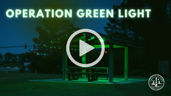 Image of a wooden shelter lit with green light bulbs. Text overlay reads, "Operation Green Light". Click to watch a video.