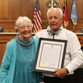 Image of the Chairman presenting a framed resolution to Mary Helen.
