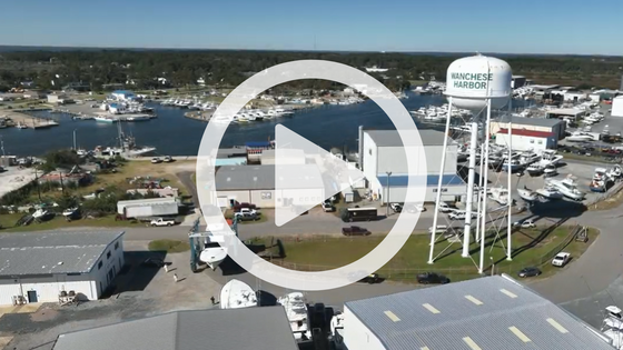 Aerial image of Wanchese harbor featuring a water tower. A play button signifies that a video about Wanchese will play when clicked.
