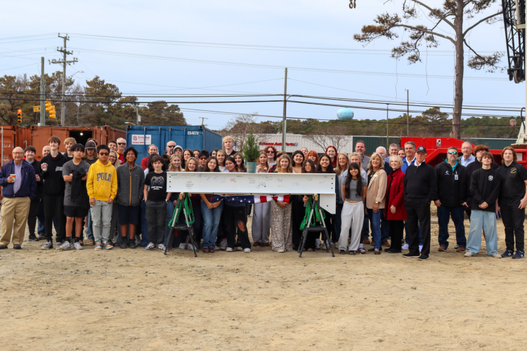 Dare County Commissioners, Board of Education members and the Early College’s inaugural Class of 2029 stand before the facility's final beam.