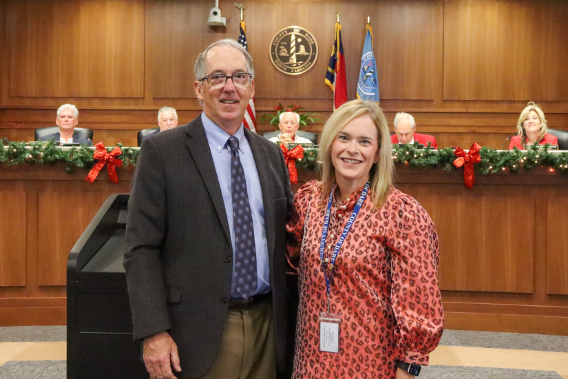 Image of Bobby Outten and Elizabeth Reilly standing at the podium during the commissioners meeting.