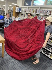 3 Knit Knights members holding large red afghan